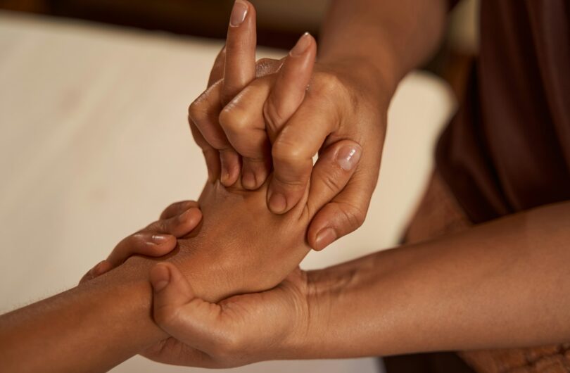 Massotherapist stretching patient digits during Thai massage session