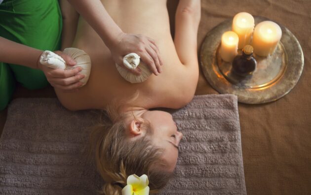 Woman getting thai herbal compress massage in spa