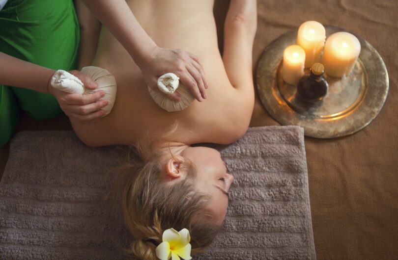 Woman getting thai herbal compress massage in spa